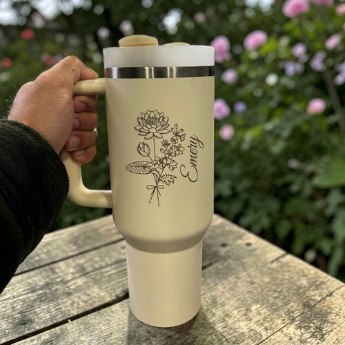 Cream Stanley 40 0z tumbler for birthday gift  with floral design and 'Emily' text, held outdoors.