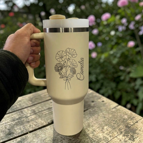Cream Stanley 40 0z tumbler for birthday gift with floral design and 'Camelia' text held by a hand outdoors.