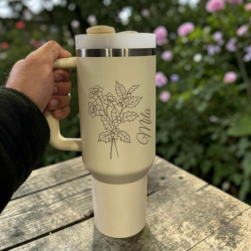 Cream Stanley 40 0z tumbler for birthday gift with floral design and 'Mila' text held by a hand outdoors.