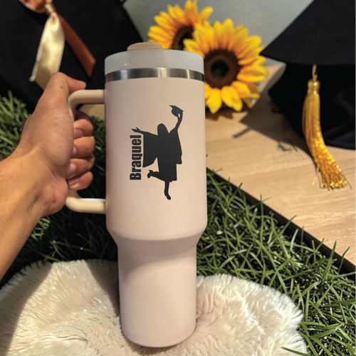 White  Stanley 40 0z tumbler with a black silhouette design held by a hand, sunflowers, and graduation cap in the background.